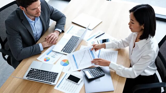 Collaborative Discussion Between Advisor And Client Over Financial Documents, Professional Setting Where Consultant Assists Asian Client Using Calculator And Shared Papers