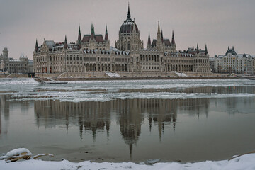 Fototapeta premium Ice floes on the Danube River with Hungarian Parliament in winter