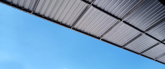 Metal sheet roof curve on blue sky. Modern construction, Metal ribbed arch span roof covering,...