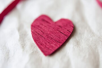 A heart shape cut from wood rests on light fabric, showcasing a simple design during a crafting activity in daylight