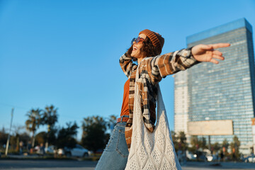 Woman arms urban sunlight carefree bohemian portrait of a young woman spreading arms on city street...