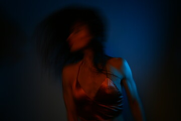 Obraz premium Young dancing woman with long hair in the dark studio iridescent colorful artistic light glows in fantasy club neon creative rays. Magic blending light, color, fantasy with sexy body girl. Art blurred