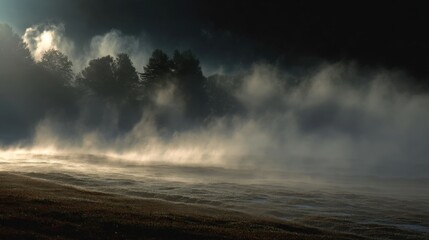 Misty morning landscape with sunrise and fog over forest and field.
