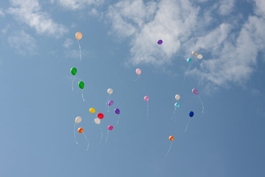 Many colorful balloons flying high in the clear blue dky