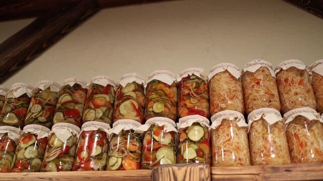 Rows of homemade pickled vegetables arranged on wooden shelves with warm rustic lighting creating cozy culinary atmosphere and highlighting colors textures and artisanal preserved produceRows of homem