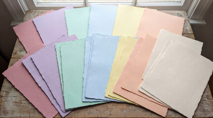 Flat lay of pastel paper sheets layered slightly to show color variety.