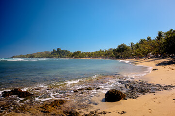 The grounds, pool and beach of the Senator Peurto Plata Hotel in the Dominican Republic, surrounded by palm trees under clear blue skies.
