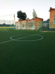 Soccer field with green turf and surrounding fence near a building