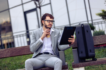 Businessman Sitting on Bench Using Tablet and Drinking Coffee