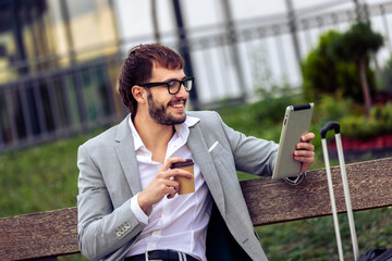 Young Businessman Using Tablet on Bench Outside Office