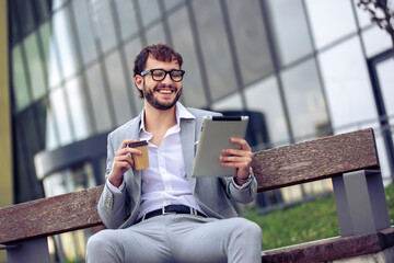 Young Businessman Using Tablet on Bench Outside Office