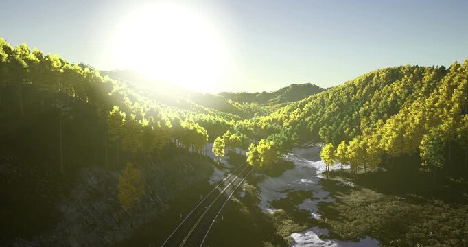 Golden sunlight illuminates vibrant green hills as morning breaks over a peaceful landscape. Railway tracks meander through the scenery, enhancing the tranquil atmosphere.
