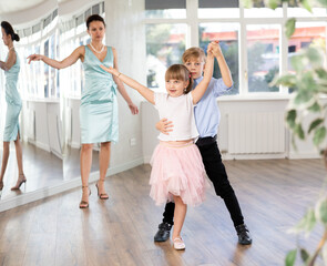 Obraz premium Boy and girl train to dance contemporary vigorous rumba during classes. Female teacher conducts class for teen students during dance workout