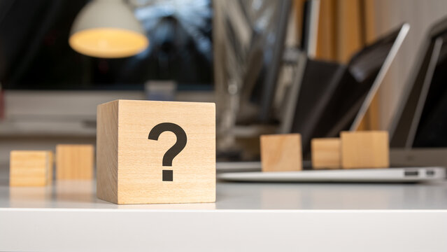 Wooden cube with question mark symbol on desk