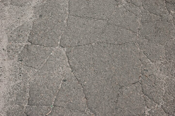 Old cracked gray asphalt surface conveying abandonment and neglect.
