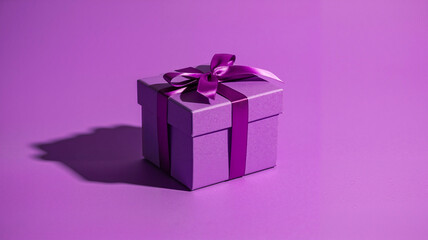 Obraz premium Purple gift box with purple ribbon on solid purple background 