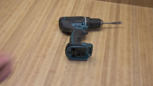 Person removing and replacing a cordless drill battery