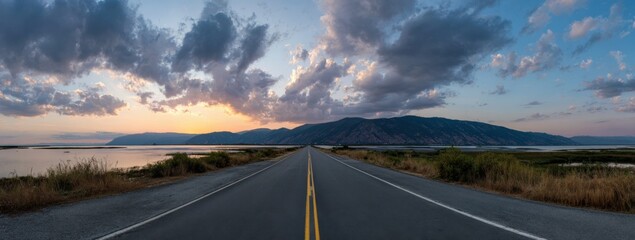 Serene road at sunset with mountains and dramatic clouds
