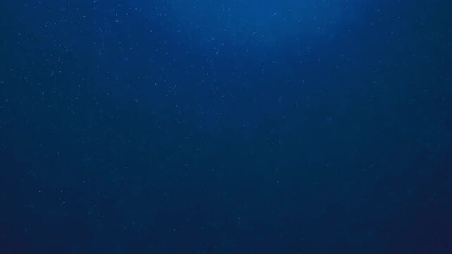 Deep blue abstract background resembling underwater depth or cosmic space with tiny floating illuminated dust particles and a soft gradient