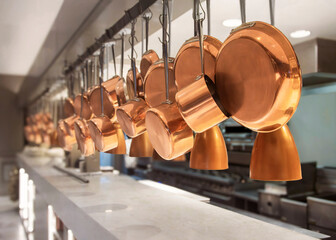 Side view of Copper pots and pans hanging in an industrial kitchen