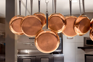 Copper pots and pans hanging in an industrial kitchen