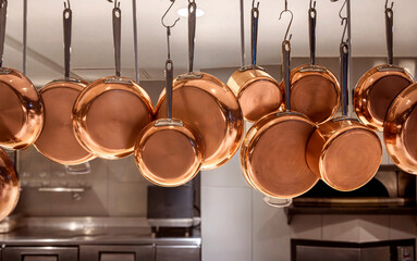 Copper pots and pans hanging in an industrial kitchen