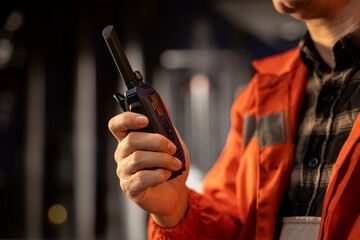 Close up of professional environmental officer communicating via radio device on offshore platform, emission tracking to manage petroleum and natural gas extraction from marine environment.