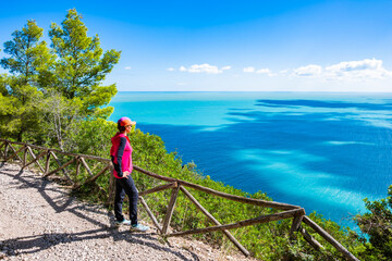 Female hiker on mountain path looking at stunning view of the Adriatic Sea in Gargano National Park, Italy, Apulia, Italy