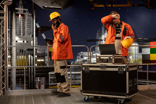 Concerned employee on offshore oil platform manages petroleum extraction using laptop, sweating and struggling to ensure safe oil extraction. Worried restless engineer in tension.