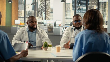 Group of specialists and medics collaborating in a hospital conference room. Healthcare staff brainstorms treatment ideas and wellness advancements through teamwork and communication.