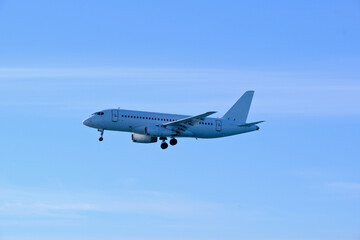 Naklejka premium White aircraft on final approach to the airfield under a bright blue sky.