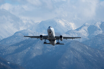 Takeoff with Stunning Mountain Backdrop. White airplane taking off against snow-capped mountains,...