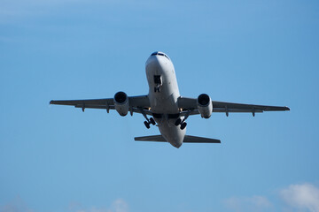 Obraz premium White commercial airplane climbing in clear blue sky after takeoff. White plane climbing after takeoff against the blue sky