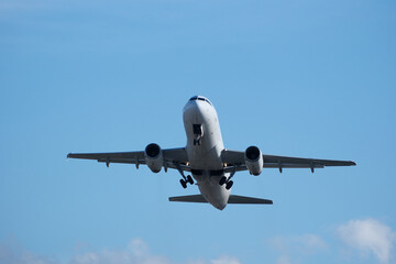 Fototapeta premium White commercial airplane climbing in clear blue sky after takeoff. White plane climbing after takeoff against the blue sky