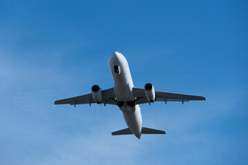 Fototapeta premium White commercial airplane climbing in clear blue sky after takeoff. White plane climbing after takeoff against the blue sky