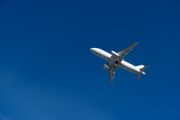 White commercial airplane climbing in clear blue sky after takeoff. White plane climbing after takeoff against the blue sky