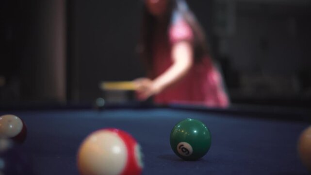 Cinematic close-up video of a woman&rsquo;s hands arranging billiard balls on a pool table before starting a game. Dark bar atmosphere with moody lighting, shallow depth of field, and a focus on leisure, ni