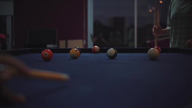 Cinematic close-up video of a woman&rsquo;s hands arranging billiard balls on a pool table before starting a game. Dark bar atmosphere with moody lighting, shallow depth of field, and a focus on leisure, ni