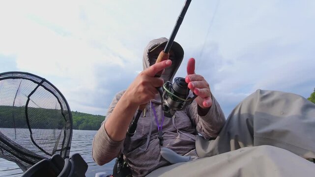 Kayak sport fishing. Angler enjoys kayak fishing at scenic coastline, casting his rod and reeling. Peaceful water shore and perfect setting at lake Simcoe, Ontario, Canada. Catch and release panfish.