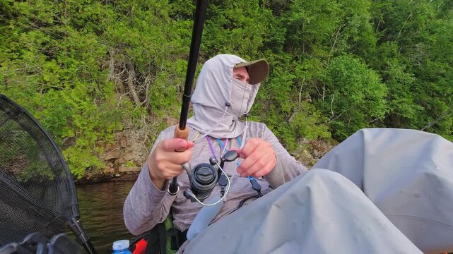 Kayak fishing solitude at lake Simcoe in Ontario, Canada, surrounded by stunning nature and tranquility. Angler enjoys solitude during hot summer evening. Man casts and reels his spinning rod.