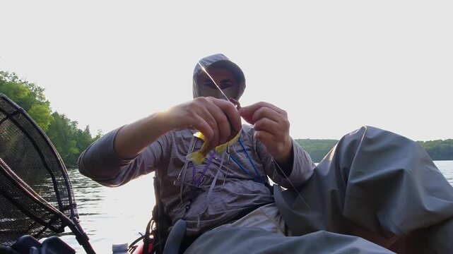 Kayak fishing solitude at lake Simcoe in Ontario, Canada, surrounded by stunning nature and tranquility. Angler enjoys solitude during hot summer evening. Man casts and reels his spinning rod.