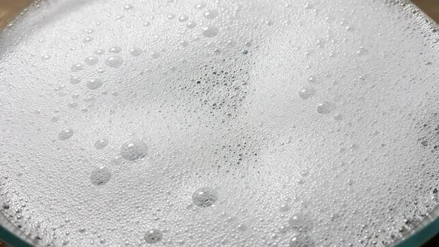 Close-up of fizzy white soap suds texture in a glass bowl, background, static, close up macro shot