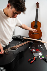 Obraz premium Installing new guitar strings. Musician installing a new string on an acoustic guitar. Acoustic guitar string replacement in progress. Guitarist stretches new strings onto the fretboard.