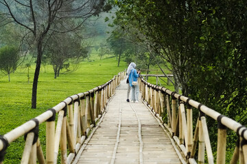 Obraz premium A couple walking on a bridge over a field