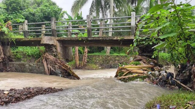 Brown river water flowing under a bridge in rural Banten with original rushing water sound