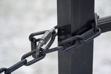 Naklejka premium Close up of a heavy duty black metal chain attached to a bollard or post for traffic control and site security in a parking area