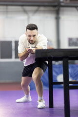 Fototapeta premium Male athlete winking holding table tennis paddle and ball