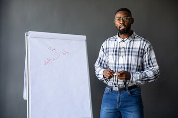 African American man 30s presenting in studio with plaid shirt, eyeglasses, flip chart and marker