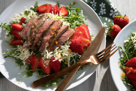 Two plates of Steak and Strawberry Salad with Arugula, Mozzarella and Orange Marmalade Dressing