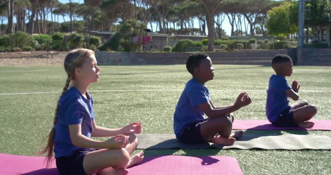 Three children after breathing cue lowering into prayer, mudra on turf mats, center child bowing